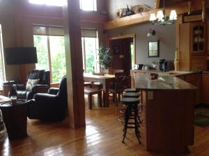 KingsclearStrong Timbers BnB的厨房以及带桌椅的起居室。