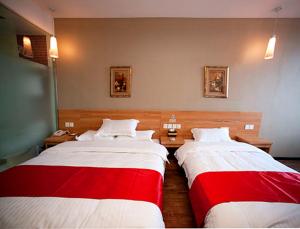 扬州尚客优连锁江苏扬州邵伯大运河店的两张位于酒店客房的床,配有红色和白色床单