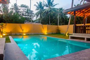 高尔Breeze Villa Unawatuna的后院的游泳池,有围栏和棕榈树