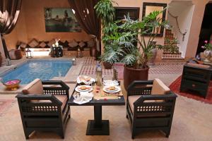 马拉喀什里亚德迪恩曼那摩洛哥传统庭院住宅的客厅设有桌子和游泳池