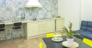 罗萨诺B&B Domus Purpurea的厨房配有黄色橱柜和桌子,上面有甜甜圈