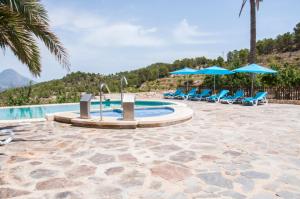 RelleuFinca El Almendral的一个带蓝色椅子和遮阳伞的游泳池