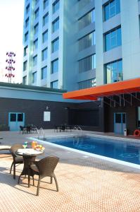 麦纳麦The Olive Hotel, Juffair的一座带椅子和桌子的游泳池位于一座建筑旁边