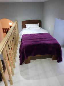 博尔若米Kiki's House的一间卧室配有一张带紫色毯子的床