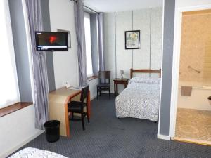 考特尼Hôtel Restaurant "Le Relais"的酒店客房配有一张床、一张书桌和一台电视。