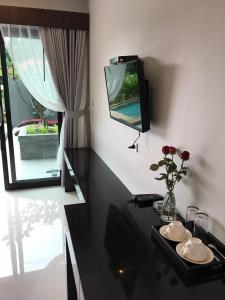 拉迈阿马里娜绿色酒店的一间配有电视的房间和一张带鲜花的桌子