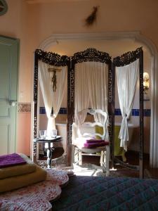 鲁西永阿姆喜酒店的一间卧室配有一张天蓬床、椅子和一张桌子