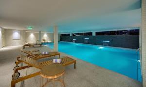 麦纳麦拉米玫瑰酒店的大楼内带长凳和桌子的大型游泳池