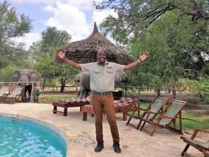 NyakisikuAfrica Safari Selous Nyerere national park的站在游泳池前,手举起的男人