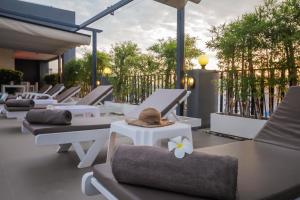 华欣Baan Nilrath Hotel - SHA Extra Plus的庭院里一排带帽子的躺椅