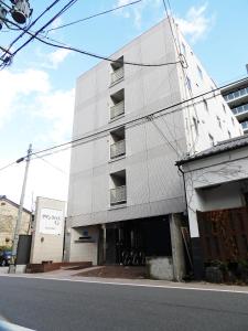 松本松本市南十字星经济型酒店的街道边带阳台的白色建筑