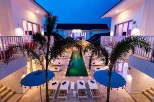 吉利特拉旺安Cocotoa Boutique Hotel & Villa的享有种有棕榈树和遮阳伞的庭院美景。
