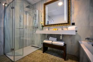 塞维利亚Hotel Legado Alcazar的带淋浴、盥洗盆和镜子的浴室