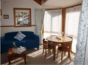 德尼利昆爱德华小屋酒店的客厅配有蓝色的沙发和桌子