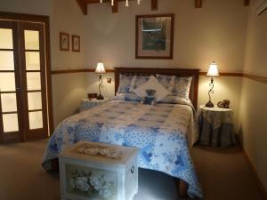德尼利昆爱德华小屋酒店的卧室配有蓝色和白色的床和两张桌子