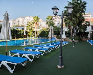 福恩吉罗拉地中海皇家公寓的游泳池旁的一排躺椅和遮阳伞
