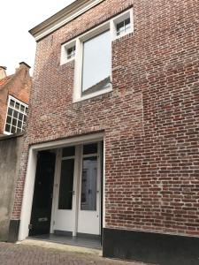 米德尔堡Mooi Genieten Studio的砖砌的建筑,有白色的门和窗户
