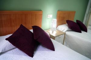 格拉纳达Antares的一间卧室配有两张带紫色枕头的床