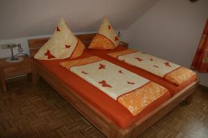 诺伊马根-德赫龙科尔斯特范葡萄酒庄&酒店的一张配有橙色和白色床单及枕头的床