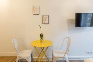 巴黎Apartments WS St Germain - Quartier Latin的一张带两把椅子的黄色桌子和墙上的电视