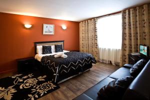埃尔森汉姆得萨利斯伦敦斯坦斯特德酒店的一间卧室拥有橙色的墙壁,配有一张床和一张沙发
