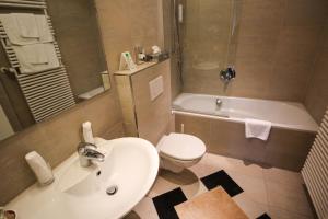 史塔卡赫祖姆格尔登欧森林酒店的浴室配有盥洗盆、卫生间和浴缸。