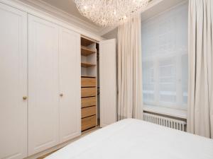 塔林哈留老城公寓的卧室配有白色的床和吊灯。
