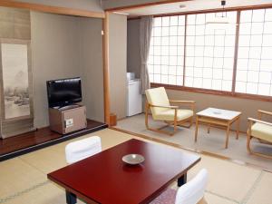 大崎市龟屋饭店的客厅配有桌椅和电视。