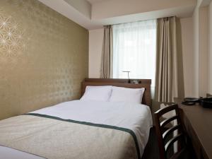 东京神田可可尼东正经济型酒店的窗户的酒店客房内的一张床位