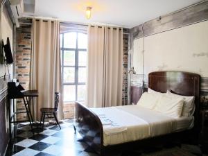 曼谷J14号住宿加早餐旅馆的一间卧室配有一张床、一张桌子和一个窗户。