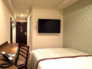 东京神田可可尼东正经济型酒店的酒店客房设有一张床和墙上的电视