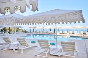 阿德耶伊波罗之星格兰帝萨龙酒店 - 仅限成人入住的游泳池旁的游泳池配有椅子和遮阳伞