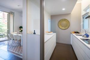巴塞罗那花园景人居公寓的一间厨房,配有白色橱柜和一间餐厅