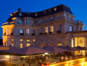 拉沙佩勒InterContinental Hotels Chantilly Chateau Mont Royal, an IHG Hotel的前面有桌子和伞的建筑