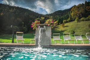兰佐莫蒂坎塞Chalet Val Concei的一组椅子,坐在一个带喷泉的游泳池周围