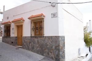 EnixVivienda Rural El Mirador de Enix的白色的建筑,有棕色的门和石墙