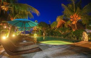 金巴兰Balangan海景简易别墅的一个带蓝伞和桌子的游泳池