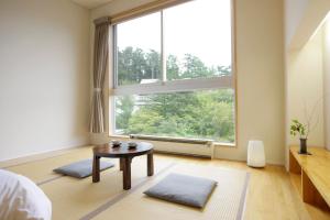 草津Kusatsu Hotel Bekkan Wata no Yu (Adult Only)的一间卧室设有桌子和大窗户