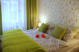 库特纳霍拉Comfortable apartments under the St. Barbara´s Cathedral的一张带绿色枕头的床和两张西红柿