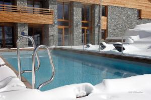 拉普德兹Lagrange Vacances l'Alpenrose的一座被雪覆盖的游泳池,位于大楼旁边