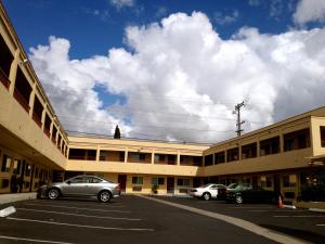 圣地亚哥Harvey's Motel SDSU La Mesa San Diego的两辆汽车停在大楼前的停车场