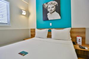 戈亚尼亚Mega Moda Goiania Hotel的一间卧室配有一张白色大床和蓝色的墙壁