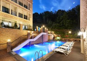 龙仁市勒松森林酒店的一座带楼梯和椅子的游泳池,位于大楼旁