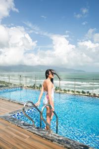 岘港哈丽娜酒店及公寓的妇女在游泳池里走下扶手
