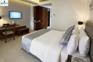达卡达卡天空之城酒店的一间卧室配有一张床、一张书桌和一台电视