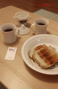 光州比于尔巴姆宾馆的一张桌子,上面放着两杯咖啡和一盘烤面包