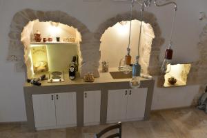 阿尔贝罗贝洛Trullo Assenzio的厨房设有两个拱门和一个带两面镜子的柜台