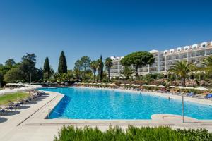 波尔蒂芒佩尼娜高尔夫度假酒店的一个带椅子的大型游泳池以及一间位于酒店后面的酒店