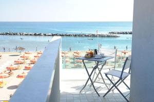 里米尼卡瓦露西奥圣马力诺住宅酒店的俯瞰海滩的阳台配有桌椅