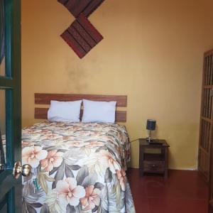 皮萨克Hospedaje Familiar Kitamayu Pisac的一间卧室配有一张带花卉床罩和桌子的床。